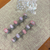 Set of hair clips with pink and clear designs on a textured surface
