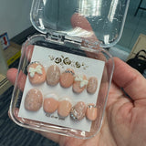 Set of nail art designs in a clear case held by a person.